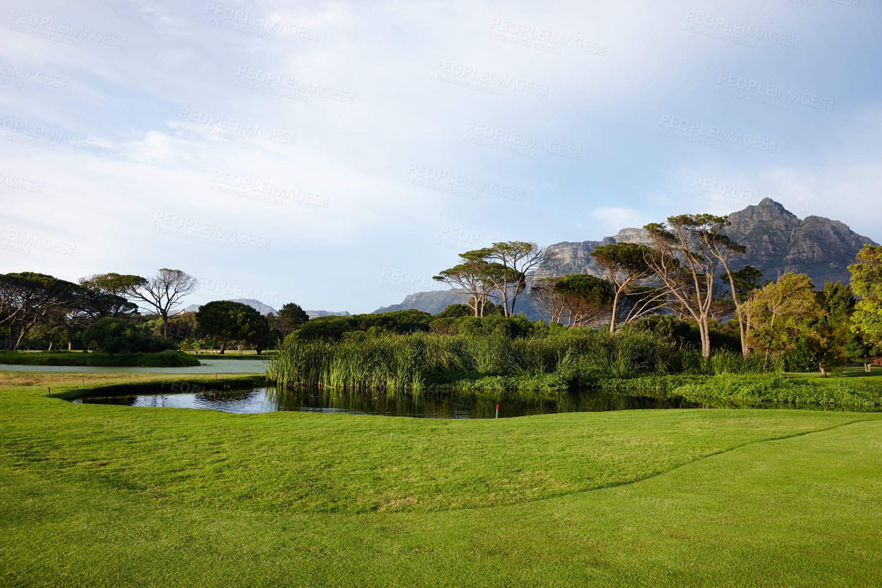 Buy stock photo Grass, sky and trees on golf course with lake, mountain and natural landscape for summer clouds in park. Nature, green and field in woods with sustainable environment, sunshine and peace with water