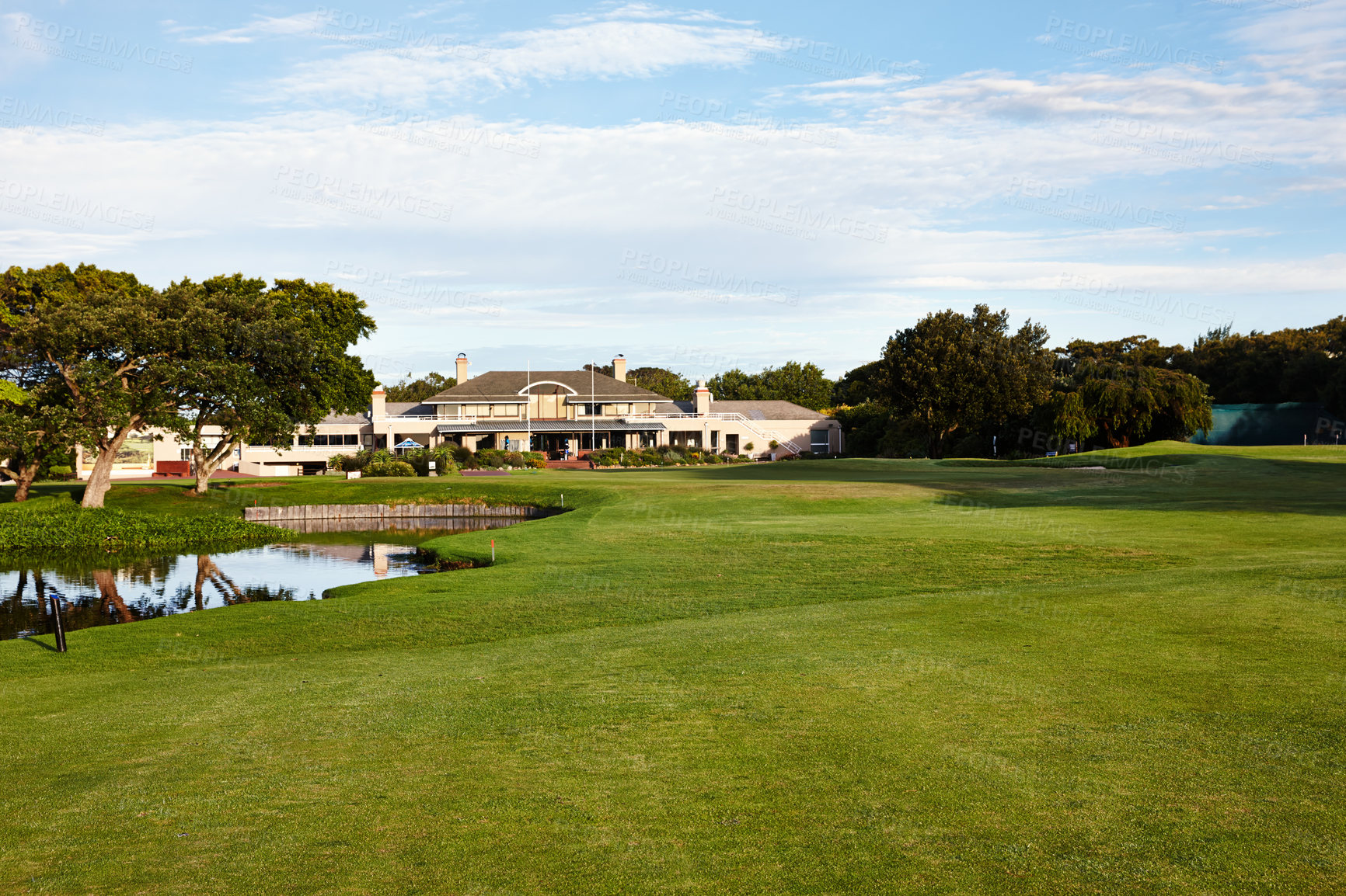 Buy stock photo Grass, sky and trees on golf course with building, lake and natural landscape with park in summer. Nature, green and field with water at sports club with sustainable environment in outdoor sunshine