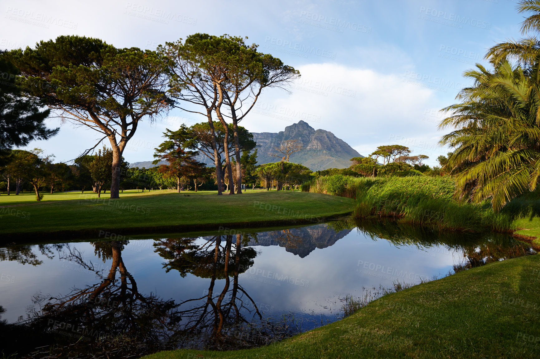 Buy stock photo Grass, sky and mountain on golf course with lake, clouds and natural landscape with reflection in park. Nature, green and water with sustainable environment, sunshine and trees for summer in Canada.