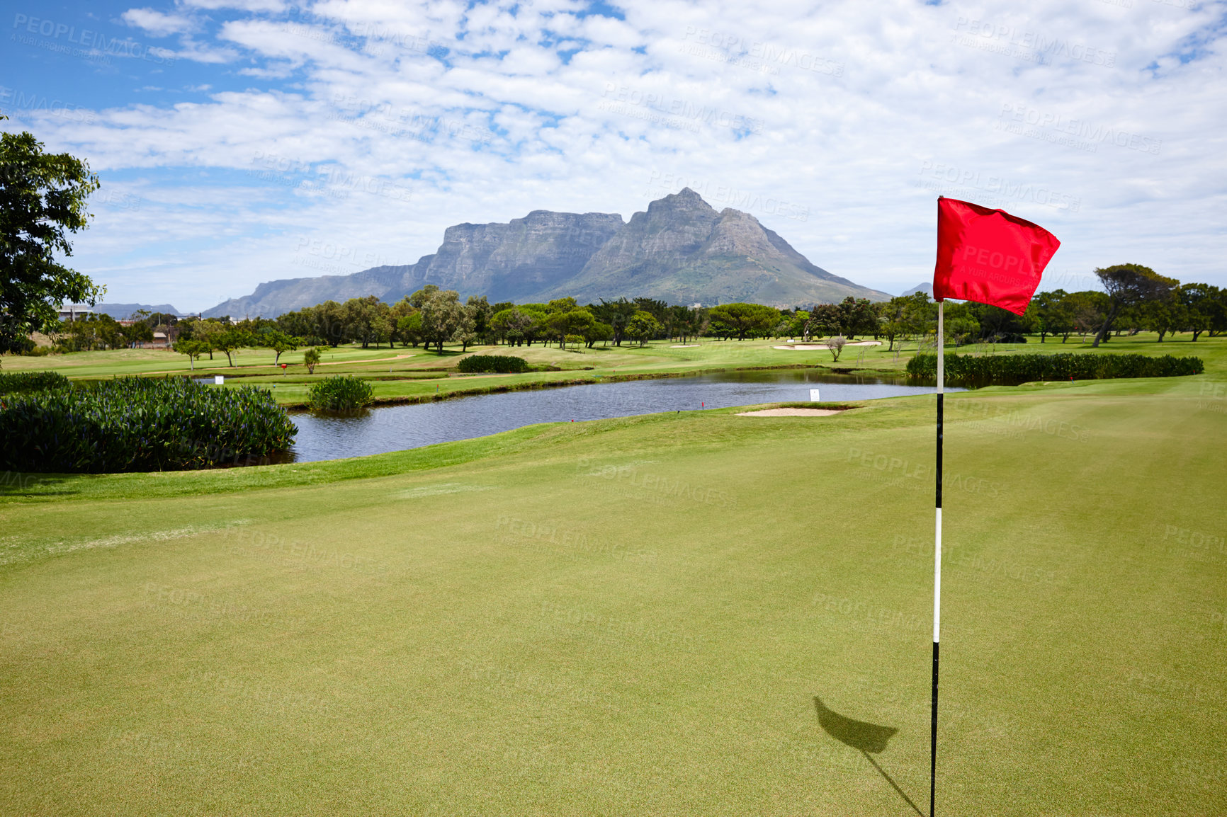 Buy stock photo Flag, hole and grass at golf course in landscape of summer on luxury holiday or vacation. Calm, morning and lawn with turf on field for sport in woods, forest or goal in park with trees and clouds