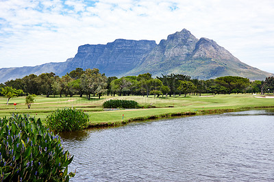 Buy stock photo Mountain, landscape and water with grass at golf course in summer on holiday or vacation. Calm, morning and lake with turf field for sport in woods, forest or nature of park with trees and plants