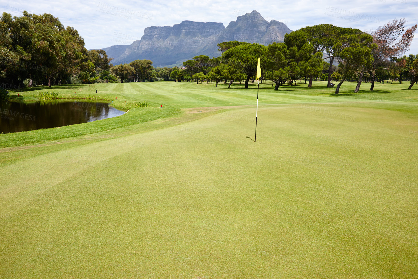 Buy stock photo Flag, hole and grass at golf course in landscape of summer on luxury holiday or vacation. Calm, morning and lawn with turf for sport in woods, forest or nature of park with water, trees and field