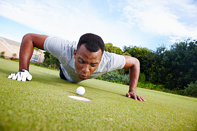 Buy stock photo Black man, golf ball and cheating on golf course for competition with greenery, grass and concentration. Male person, fitness and blowing for activity with sportswear, professional and train outside 