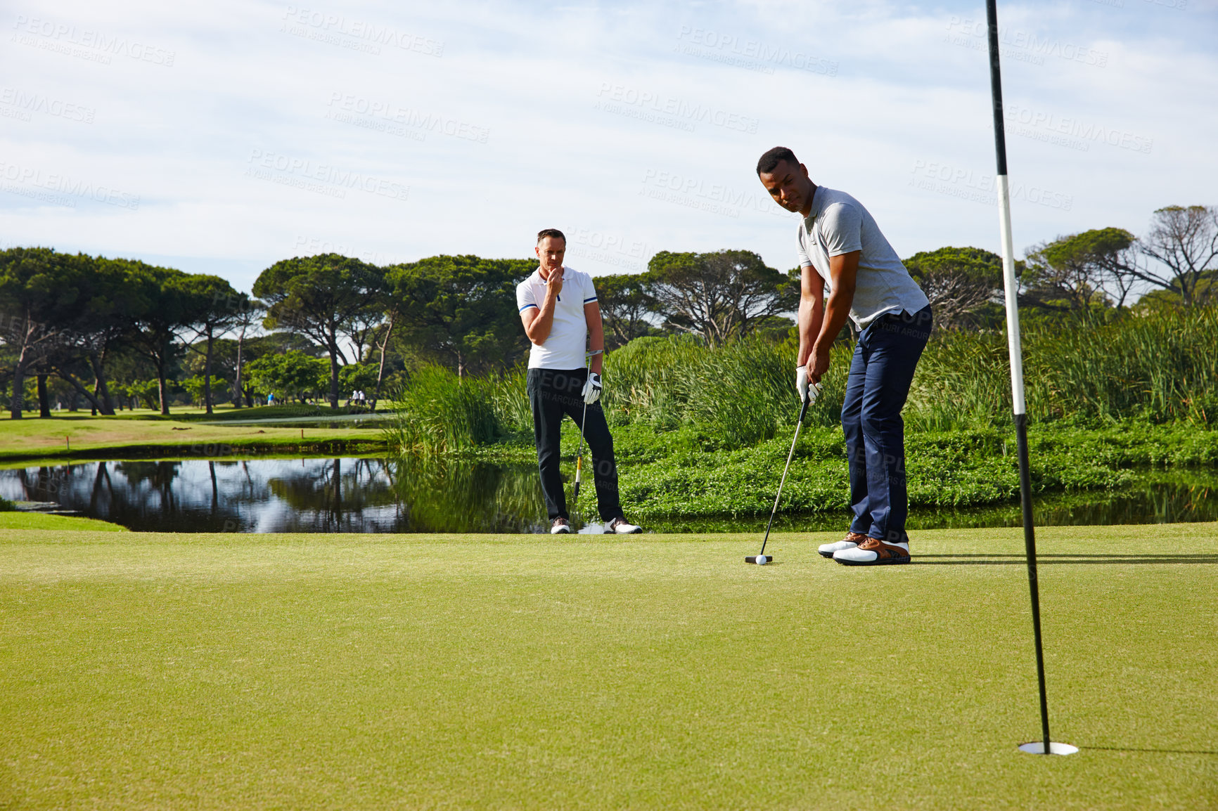 Buy stock photo Man, friends and playing with club on golf course for stroke, score or point in outdoor competition. Male person, people or golfer aiming for hole, target or par on green grass or field in nature