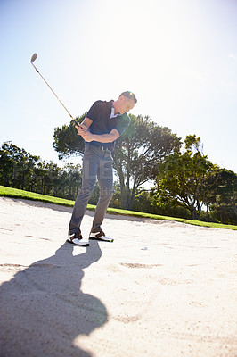 Buy stock photo Man, golfer and swing with club in sand pit by grass field for point, score or par in outdoor nature. Male person or sports player hitting ball out of dirt on green lawn or golf course with blue sky