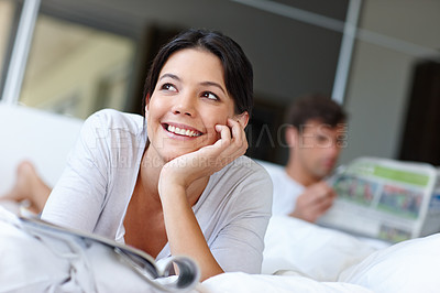 Buy stock photo Shot of a beautiful woman lying in bed with a magazine 