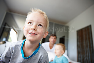 Buy stock photo Child, smile and thinking in house for childhood, development and happiness for relax and fun indoor. Boy or kid and cheerful with idea for play with father or family with sibling bonding on weekend