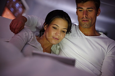Buy stock photo Cropped shot of a couple watching movies on a digital tablet while sitting in bed
