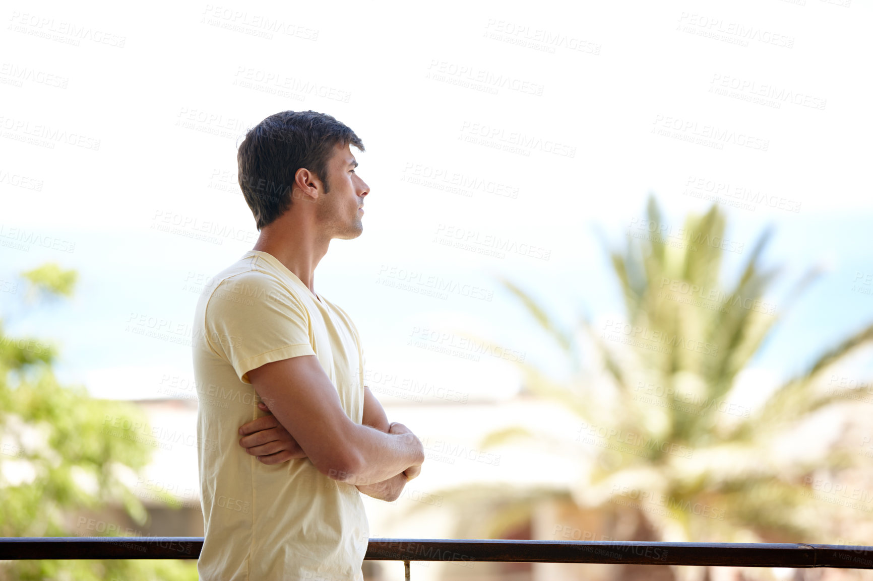 Buy stock photo A lonely man standing on holiday standing on a balcony and looking at the view at a summer vacation resort. A frustrated male feeling sad and depressed while looking thoughtful and serious at a hotel