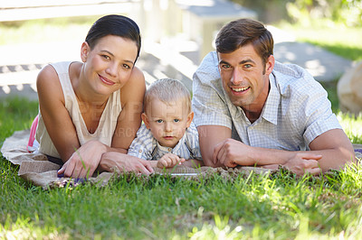 Buy stock photo Cropped shot of a cute family lying outdoors on a summer's day 