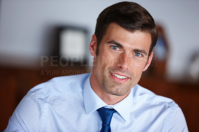 Buy stock photo Portrait of a handsome businessman sitting in his office. Smiling professional businessman looking positive. Happy confident handsome smart young adult entrepreneur, leader, and manager in a office