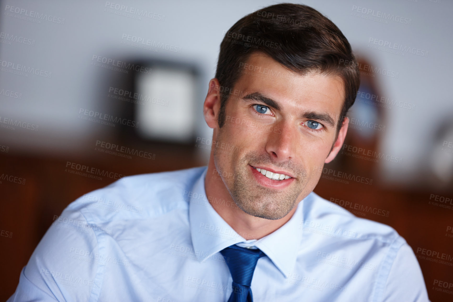 Buy stock photo Portrait of a handsome businessman sitting in his office. Smiling professional businessman looking positive. Happy confident handsome smart young adult entrepreneur, leader, and manager in a office