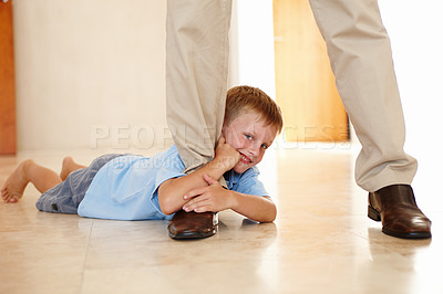 Buy stock photo Leg, child and holding on parent in portrait, play and hanging on father for game on floor in home. Male person, kid and relax on tile or clinging for support, boy and smile for funny joke or happy