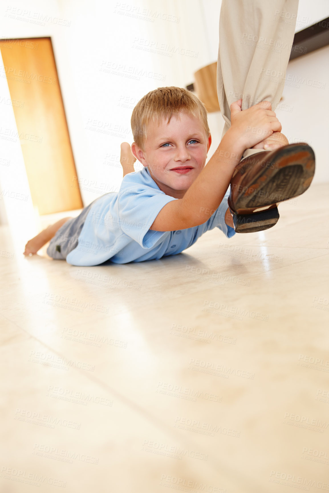 Buy stock photo Leg, child and parent dragging in portrait, play and hanging on father for game on floor in home. Male person, kid and relax on tile or clinging for support, boy and smile for funny joke or happy