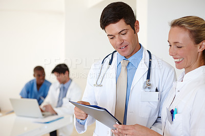 Buy stock photo Shot of a male doctor and a female nurse discussing medical records