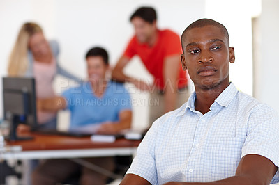 Buy stock photo Shot of a male designer looking focussed while his colleagues work in the background