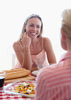 Buy stock photo Woman, smiling and talking at lunch with table, food and guests at home. Female person, happy and cheerful in conversation with family, people and relaxed in house for celebration, event or feast