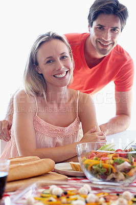 Buy stock photo Portrait, couple and living room with salad at table eating together for lunch. Married, man and woman on romantic honeymoon at house sitting in lounge with vegetables on diet for healthy wellbeing