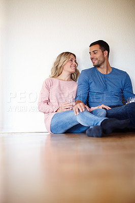 Buy stock photo Shot of a happy young couple sitting on their living room floor