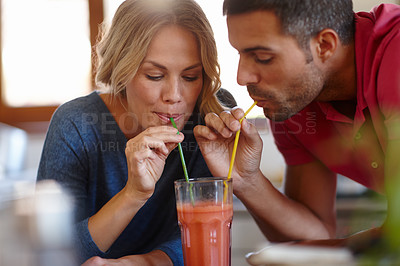 Buy stock photo Happy couple, juice and sharing in house with drink, enjoy and color straw for fun together. Love, milkshake and happiness of man with woman in home for romantic relationship, dating and glass