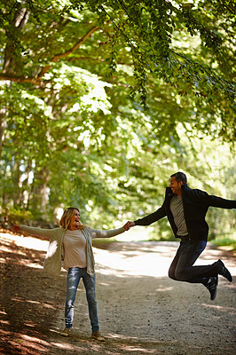 Buy stock photo Couple, holding hands and play in park, jump and commitment to relationship in outdoor nature. Happy people, bonding and care in healthy marriage, romance and together on vacation or holiday date