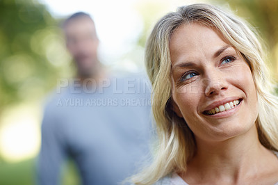 Buy stock photo Woman, looking and smiling outdoor with man in background by nature for park walk, happiness and date. Female person, happy and together as couple for love, romance and relax or mental health