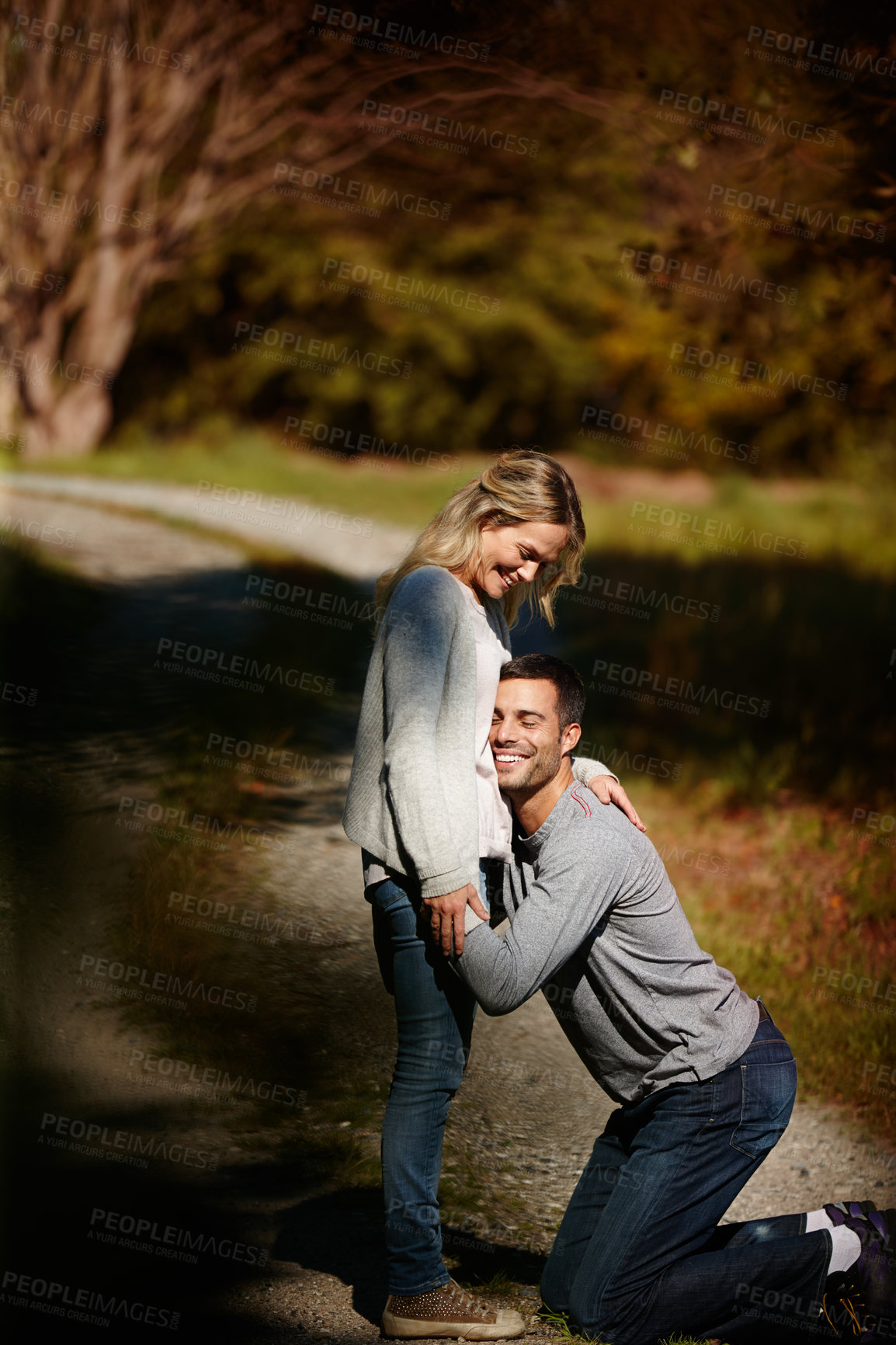 Buy stock photo Couple, hug and stomach in park for love, knees and commitment to relationship in outdoor nature. Happy people, bonding and embrace in marriage, celebrate and pregnancy on vacation or holiday date