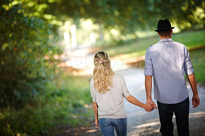 Buy stock photo Back view of couple, hand holding and walking in park for love, bonding with care and support in healthy relationship. Man, woman and outdoor for date with romance, trust and commitment for marriage
