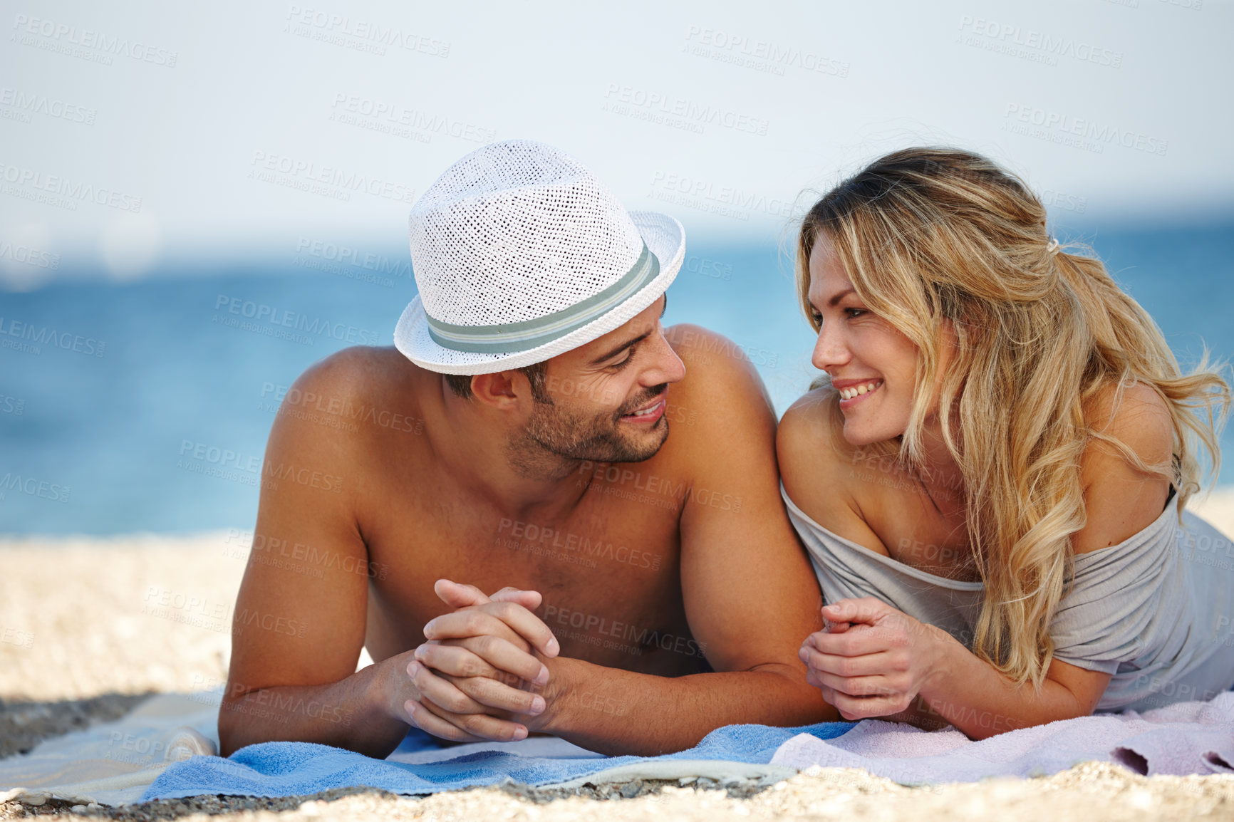 Buy stock photo Shot of a happy young couple lying on the beach