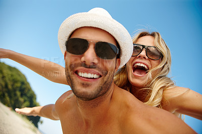 Buy stock photo Couple, sunglasses and flying on vacation, smile and peace at beach or game by blue sky. People, piggyback and tropical island for bonding on weekend, outdoor nature and love for marriage or romance