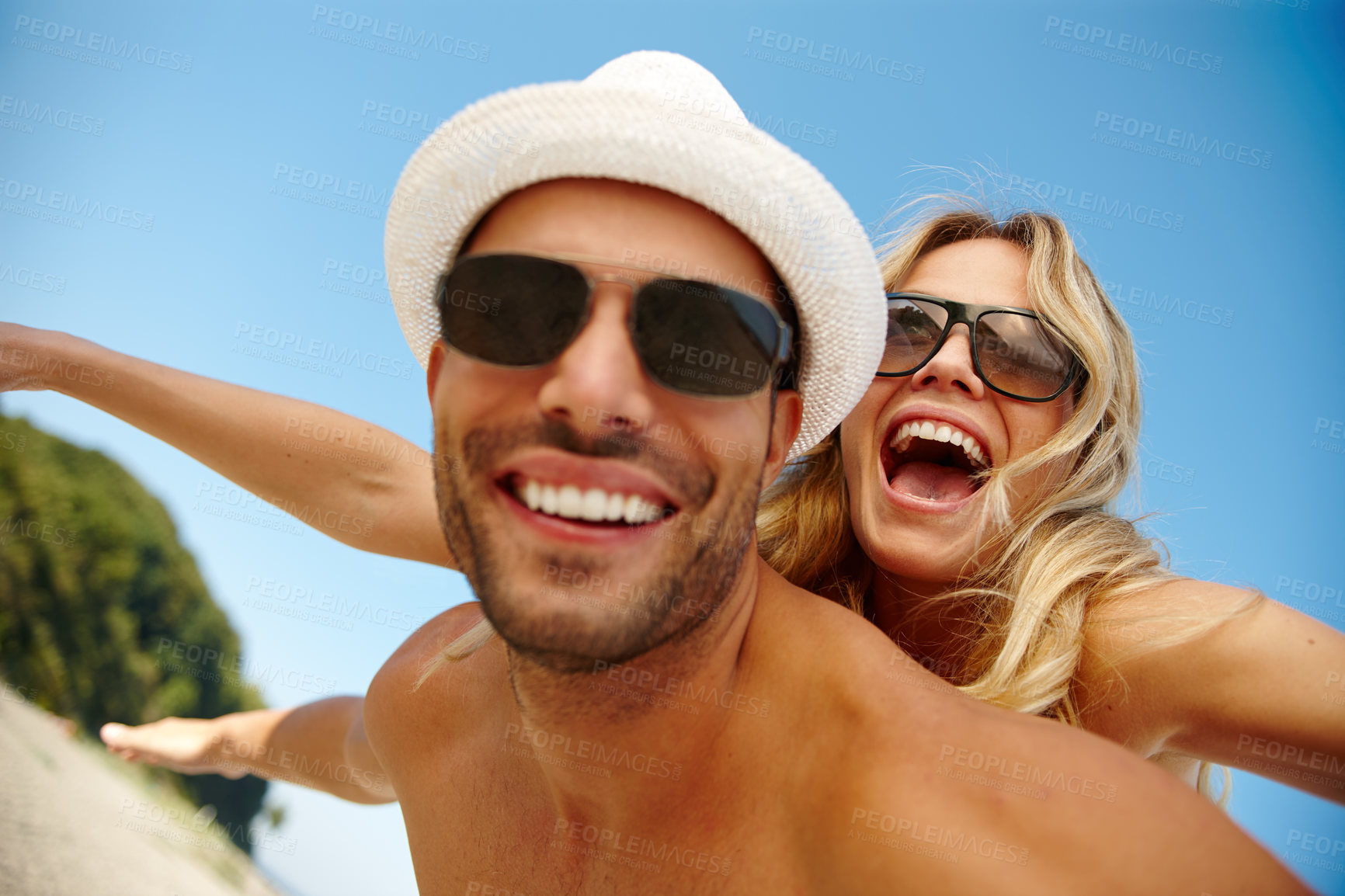 Buy stock photo Couple, sunglasses and flying on vacation, smile and peace at beach or game by blue sky. People, piggyback and tropical island for bonding on weekend, outdoor nature and love for marriage or romance