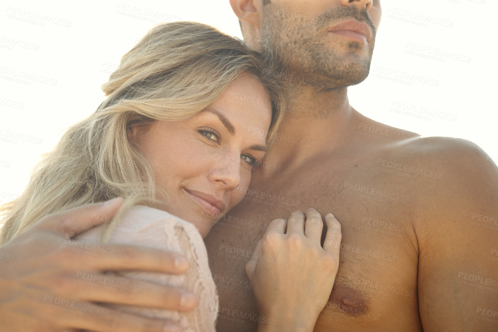 Buy stock photo Head and shoulders portrait of an attractive young woman embracing her husband on a sunny day