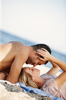 Buy stock photo Shot of an affectionate young couple enjoying a romantic day at the beach