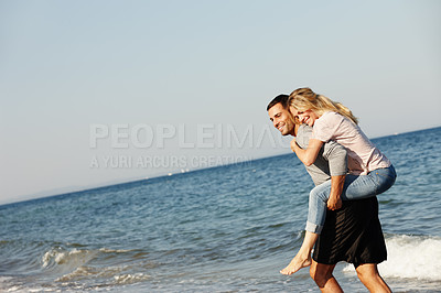 Buy stock photo Couple, ocean waves and piggyback on vacation, smile and peace at beach or game by blue sky. People, happy and tropical island for bonding on weekend, outdoor nature and love for marriage or romance
