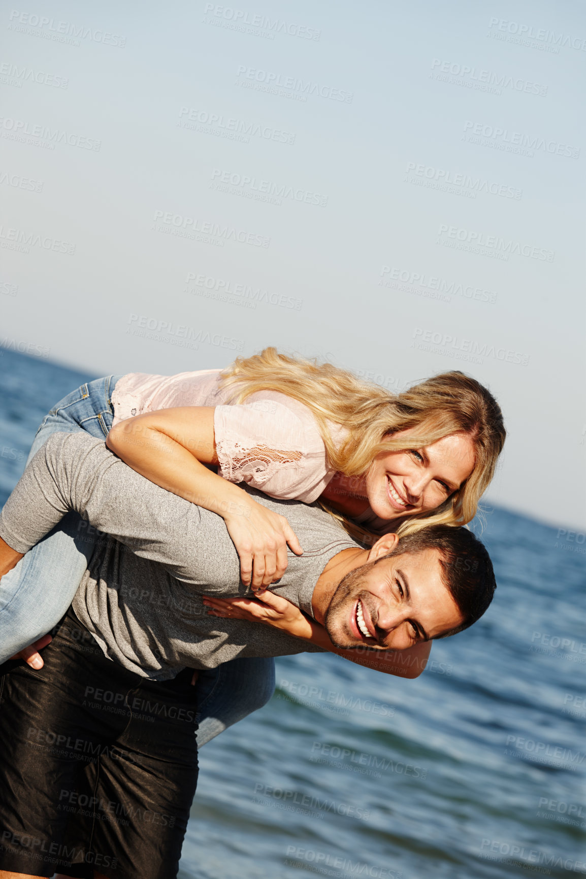 Buy stock photo Couple, portrait and piggyback on vacation, ocean and peace at beach or game by blue sky. People, happy and tropical island for bonding on weekend, outdoor nature and love for marriage or romance