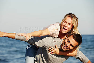 Buy stock photo Couple, flying and piggyback on vacation, smile and peace at beach or game by blue sky. People, happy and tropical island for bonding on weekend, outdoor nature and love for marriage or romance