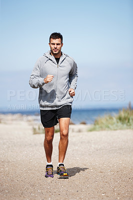 Buy stock photo Man, running and beach on sand in morning for fitness, exercise and health with hoodie. Athlete, jog and ocean in nature with shoes by sea for motivation, wellness and cardio workout or performance