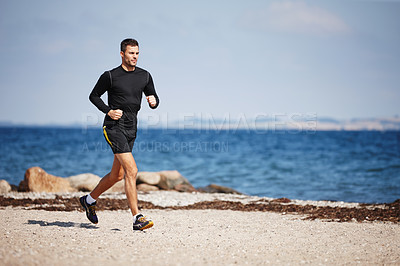 Buy stock photo Shot of a handsome young man running on the beach