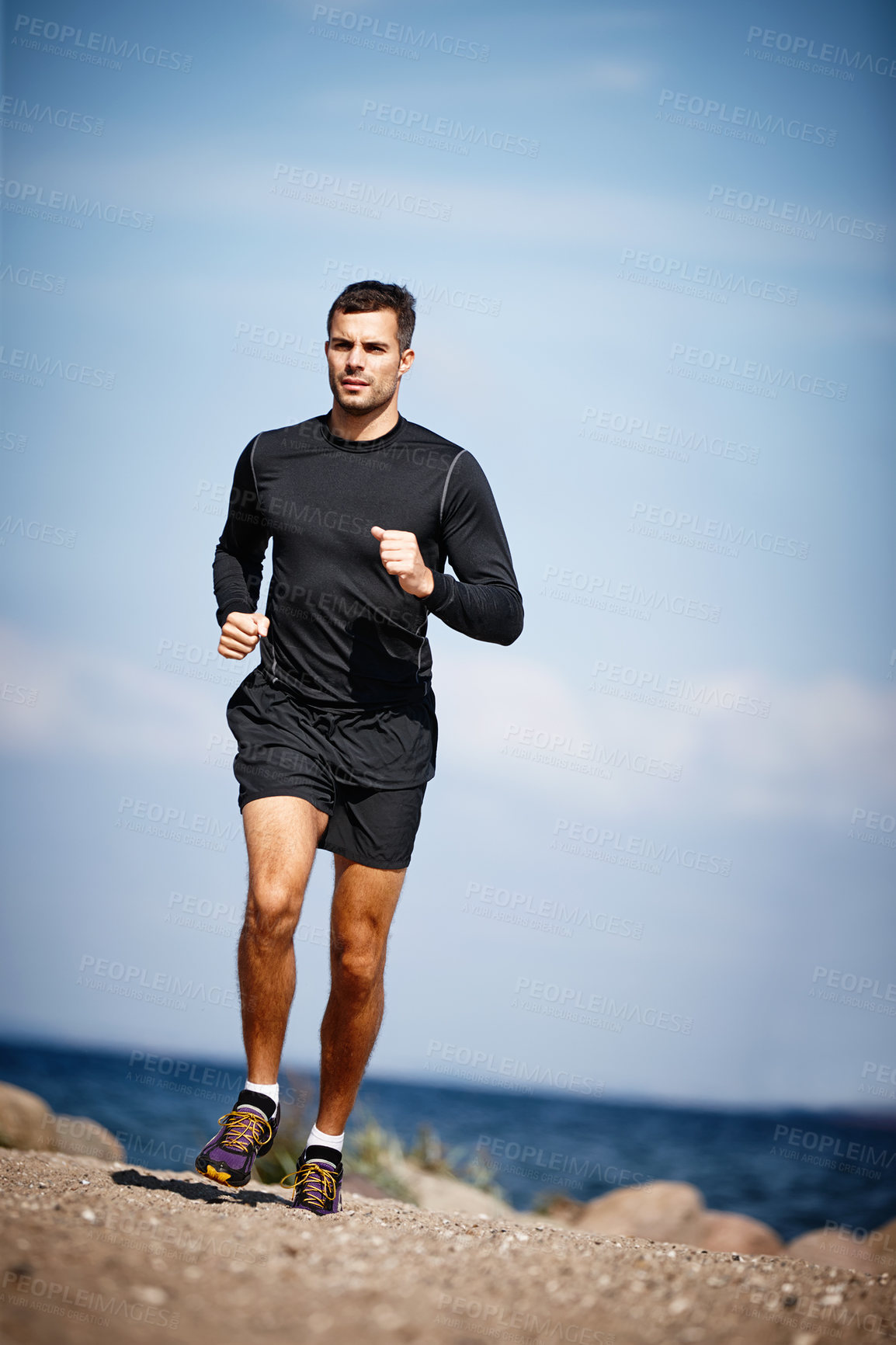 Buy stock photo Shot of a handsome young man running on the beach