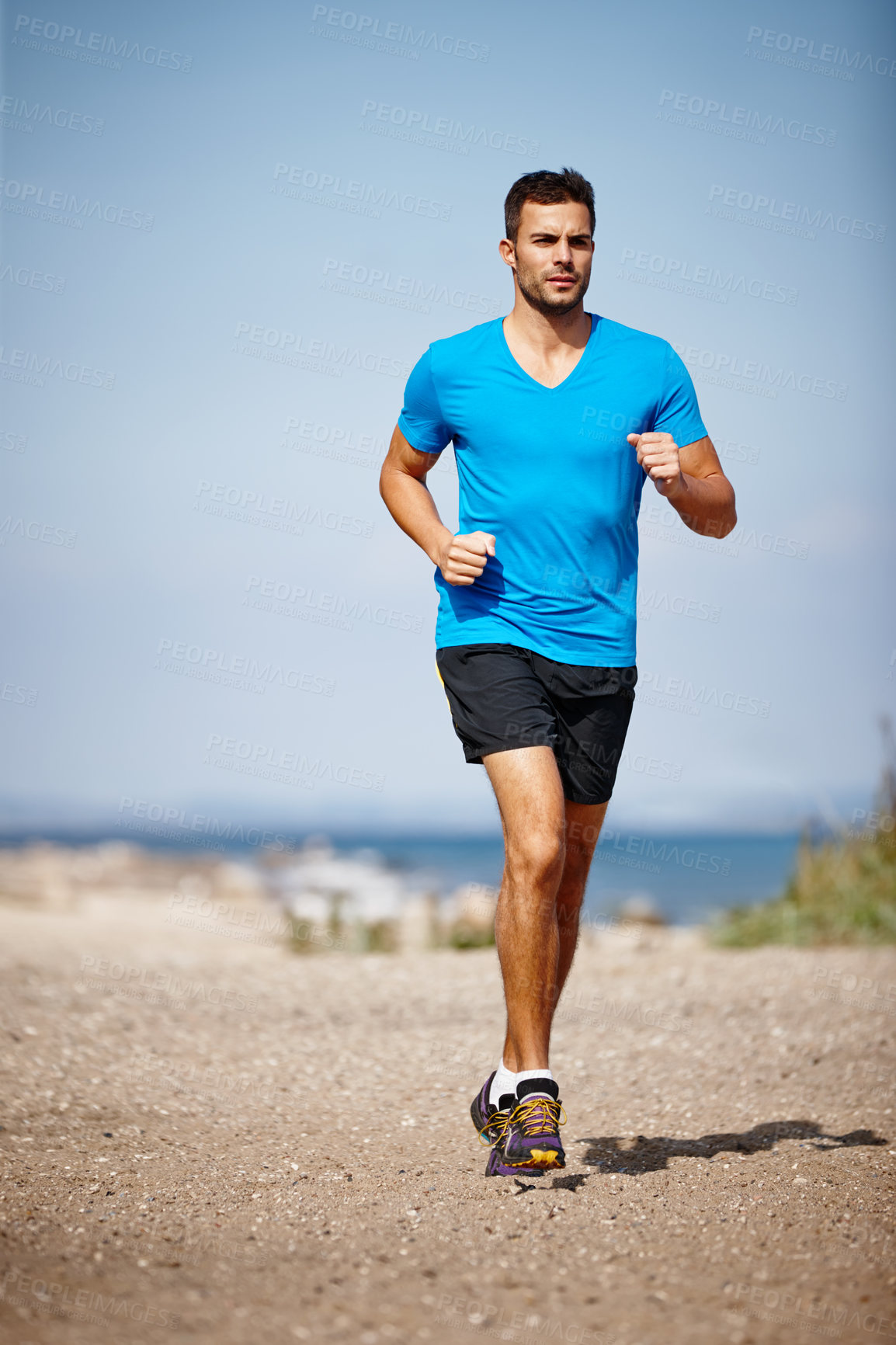 Buy stock photo Shot of a handsome young man running on the beach