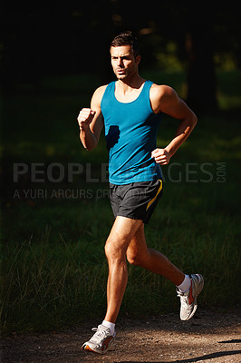 Buy stock photo Shot of a handsome young man taking a jog outdoors