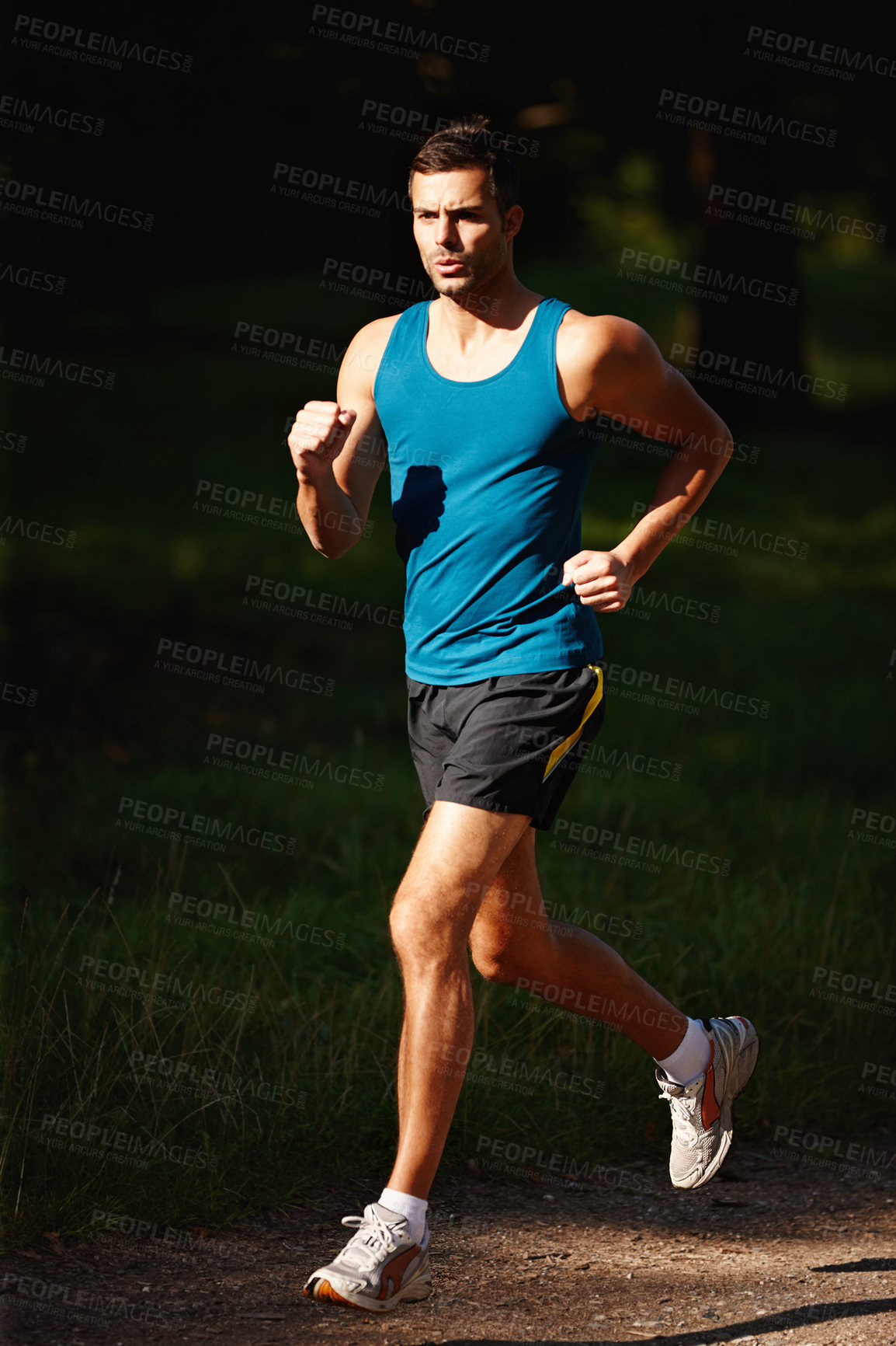 Buy stock photo Shot of a handsome young man taking a jog outdoors