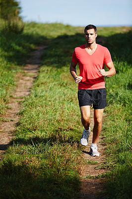 Buy stock photo Shot of a handsome young man taking a jog outdoors