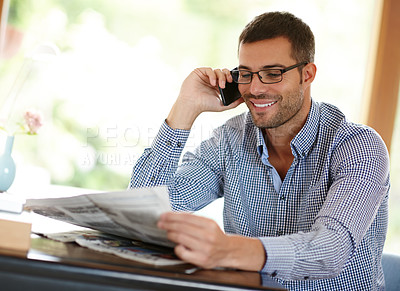 Buy stock photo Man, home and phone call while reading a newspaper, morning routine and article for information. Male person, smile and app for conversation or networking, internet and story or weekend connection