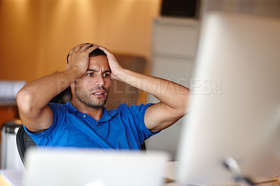 Buy stock photo Shot of an attractive young man looking worried at his desk