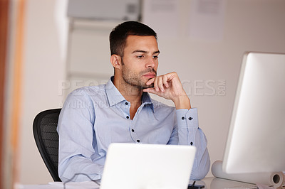 Buy stock photo Shot of an attractive young man looking at a computer screen