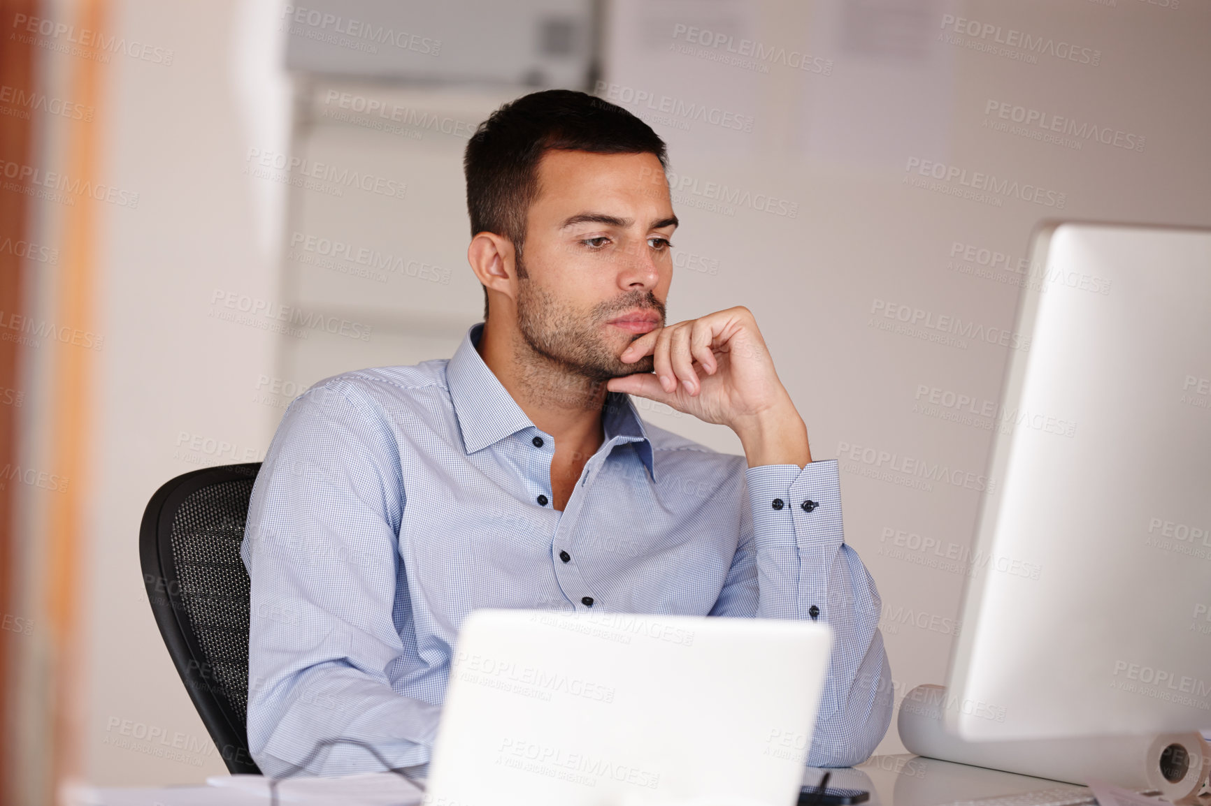 Buy stock photo Shot of an attractive young man looking at a computer screen