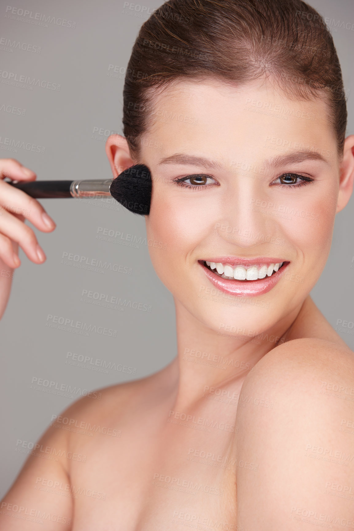 Buy stock photo Studio shot of a beautiful woman applying blush to her cheeks