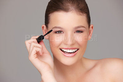 Buy stock photo Studio portrait of a beautiful woman applying mascara