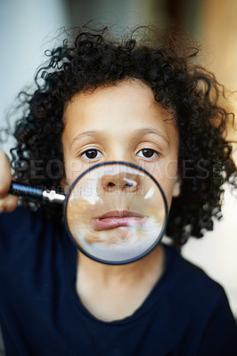 Buy stock photo Shot of a little boy holding a magnifying glass to his mouth and pulling faces